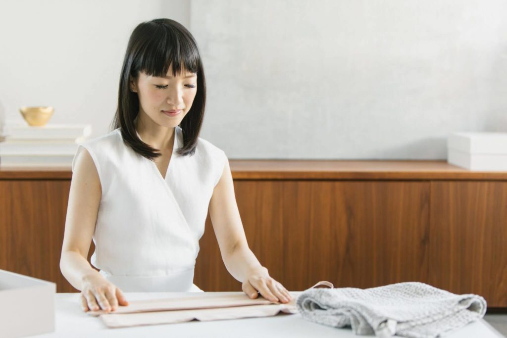 Image of Marie Kondo, folding clothes at a table