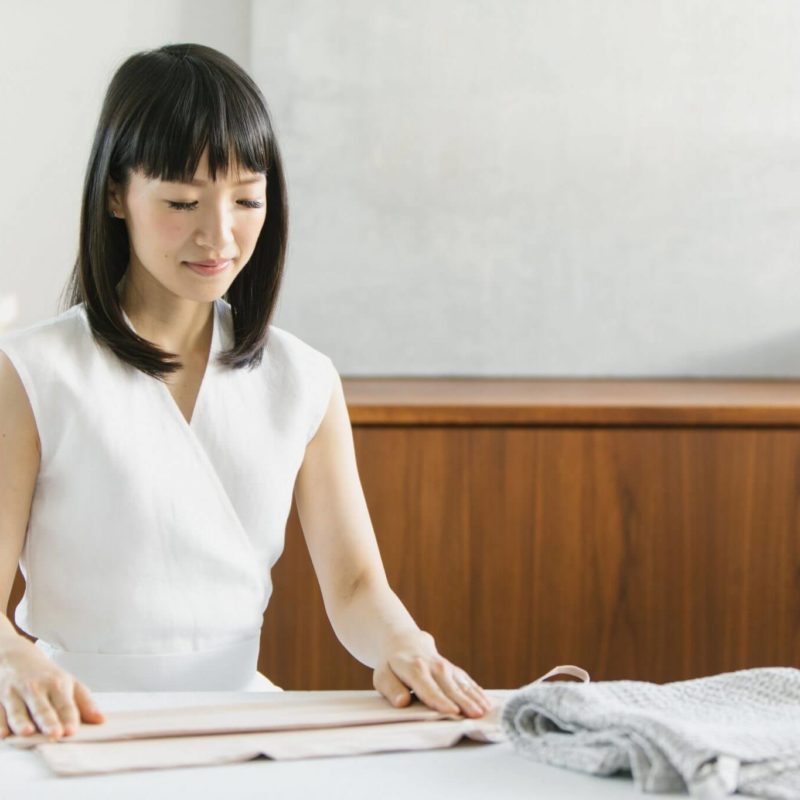 Image of Marie Kondo, folding clothes at a table