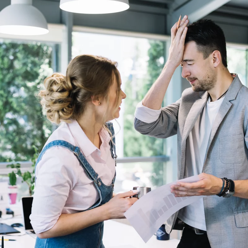 man slapping forehead beside woman, in an office setting