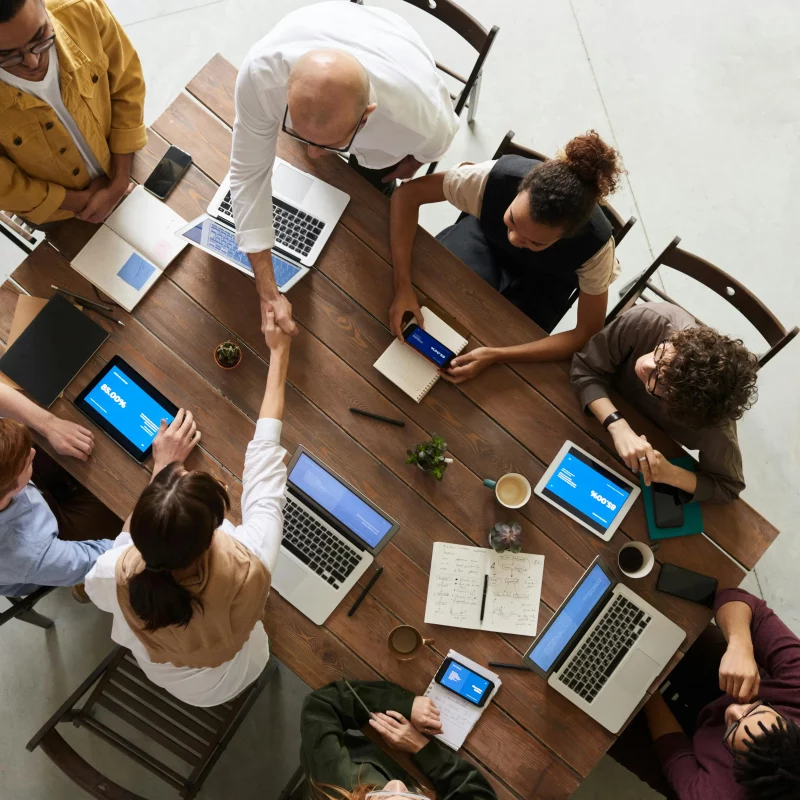 An overhead shot of a group of people sat around a desk in an office setting