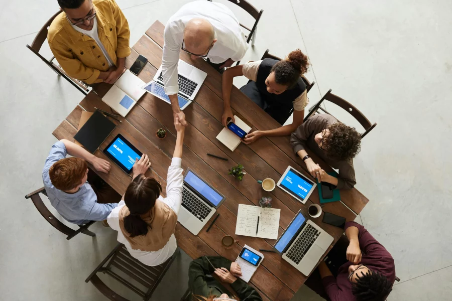 An overhead shot of a group of people sat around a desk in an office setting