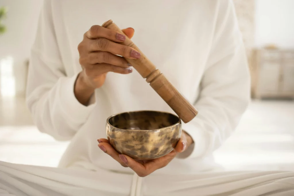 Image of a woman wearing all white holding a Tibetan singing bowl