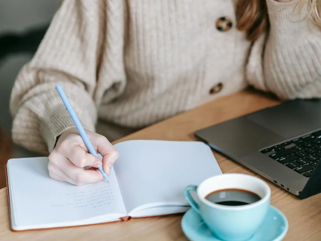 woman sat down at a table writing in a notebook