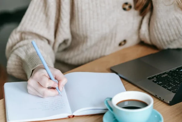 woman sat down at a table writing in a notebook