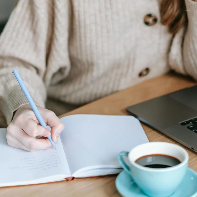 woman sat down at a table writing in a notebook