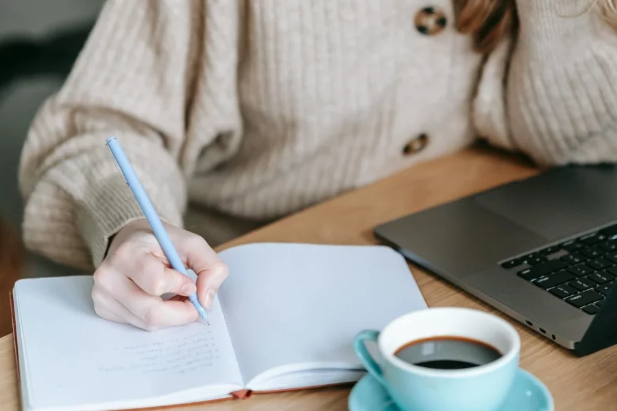 woman sat down at a table writing in a notebook