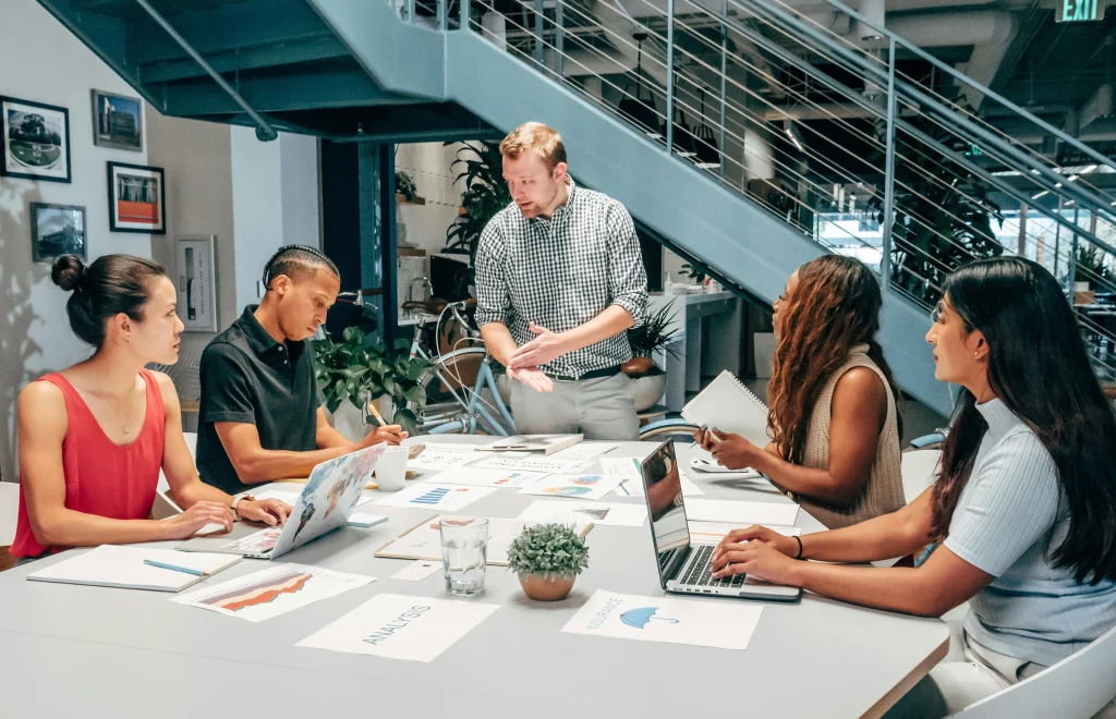 5 people sat down at a table having a work meeting